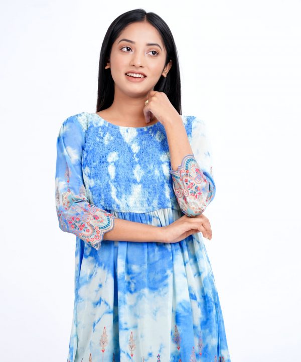 Sky blue tunic in printed Georgette fabric. Designed with a round neck and three-quarter sleeves. Smoked detailing at the top front. Gathers from the waistline.